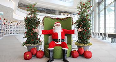 Santa seated in a library with arms wide