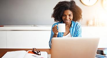 Woman on her laptop holding a cup of coffee