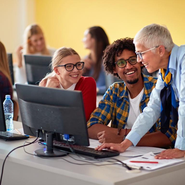 Teacher and students working on computer smiling